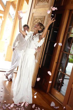 Groom watching While White Dressed Bride throwing Flowers into Air